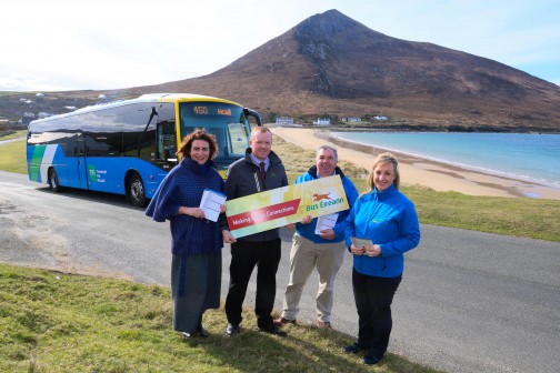 Four people stand in front of a bus on Achill Island